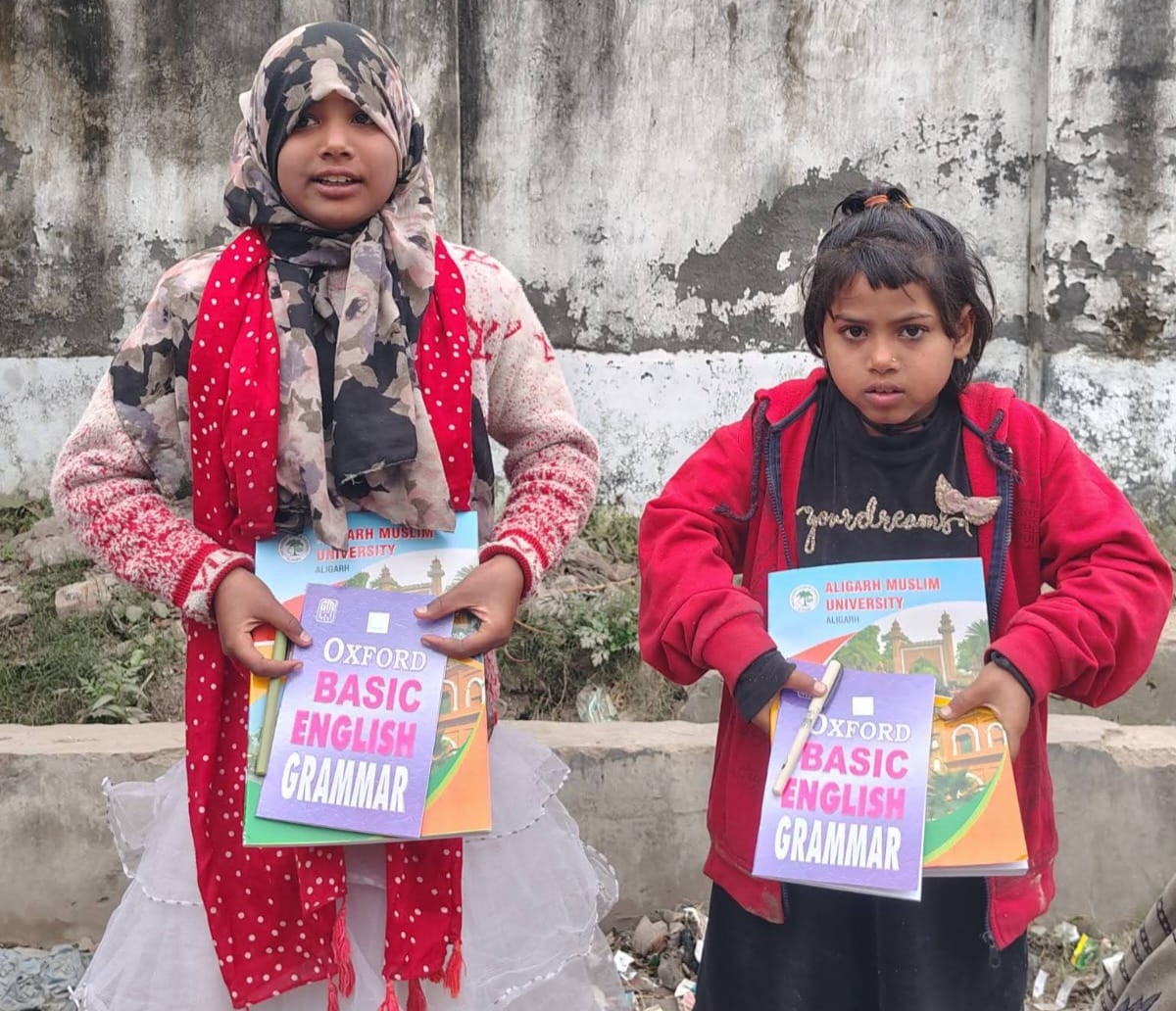 Two girls holding donated English grammar books