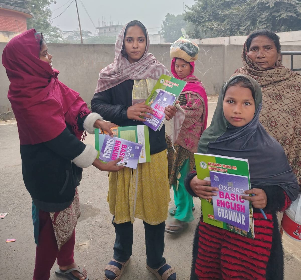 Volunteers distributing English grammar books to children